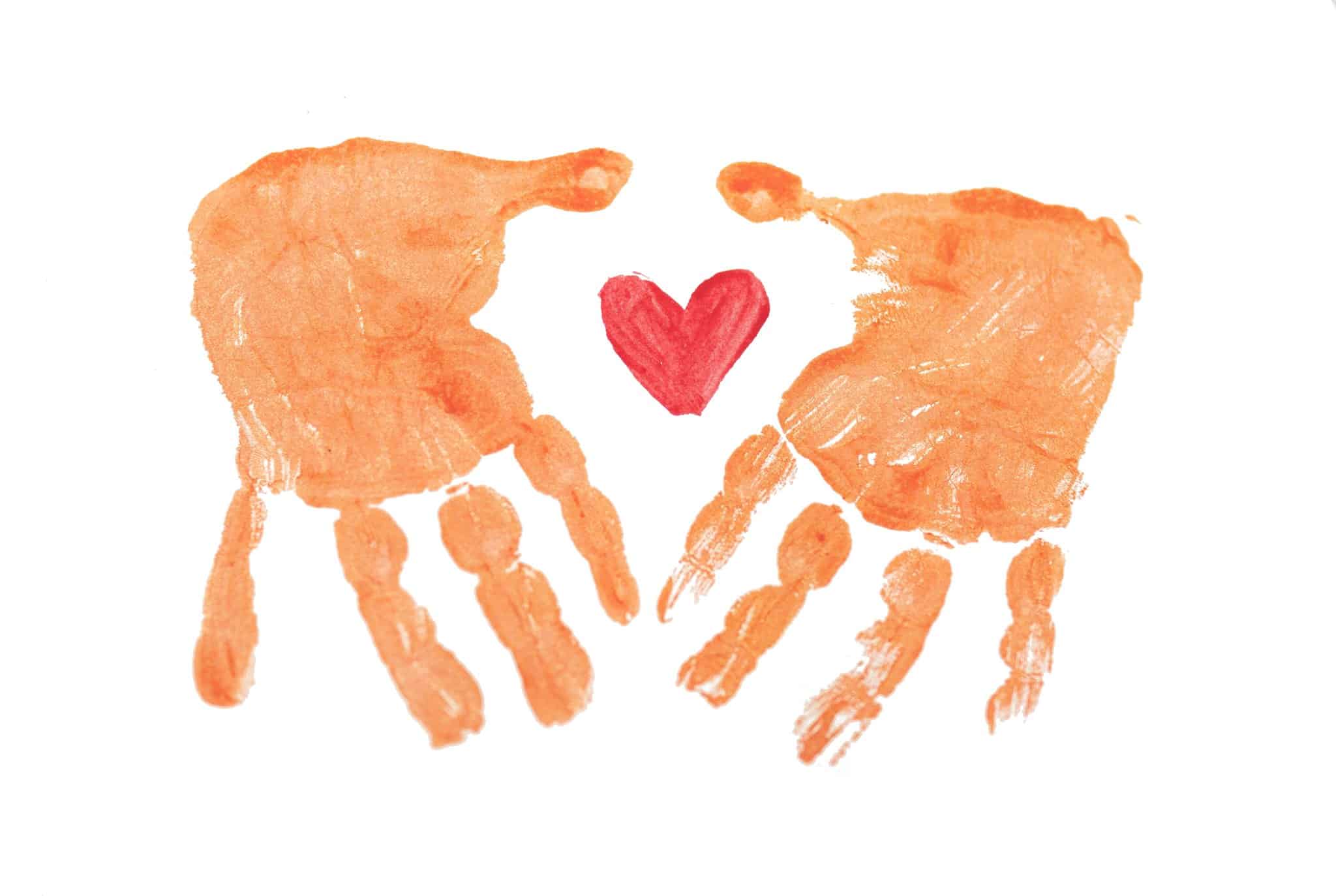 Two orange hand prints frame a red painted heart.