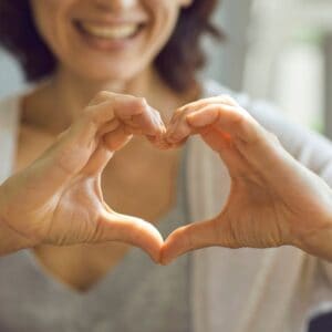 A woman makes a heart with her hands.