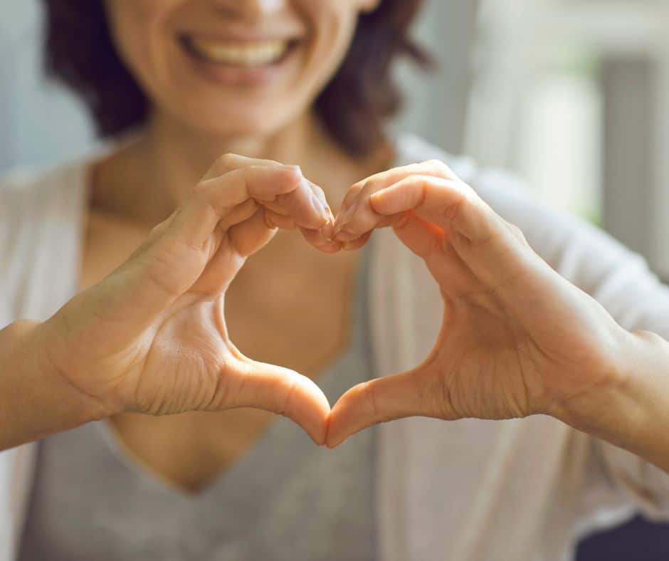 A woman makes a heart with her hands.