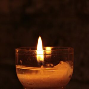 A solitary candle burns in the dark.