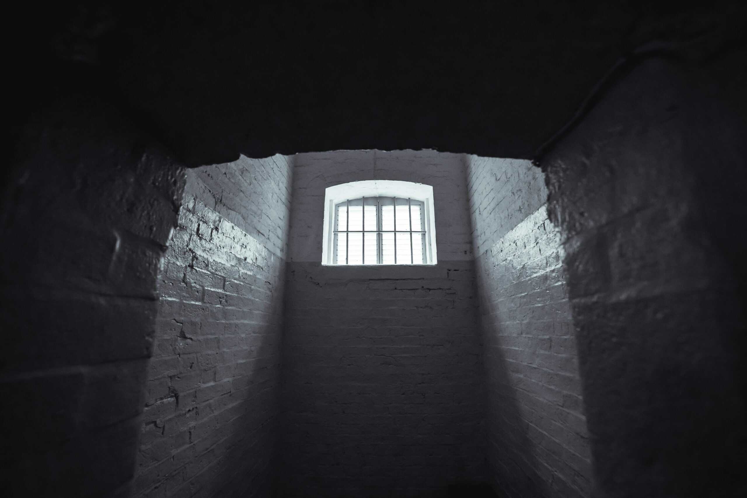 Light streams into a cell block from a barred window.