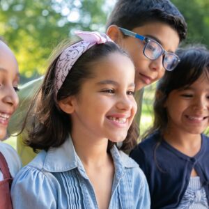 A group of children watch with bright smiles as someone does something off camera.