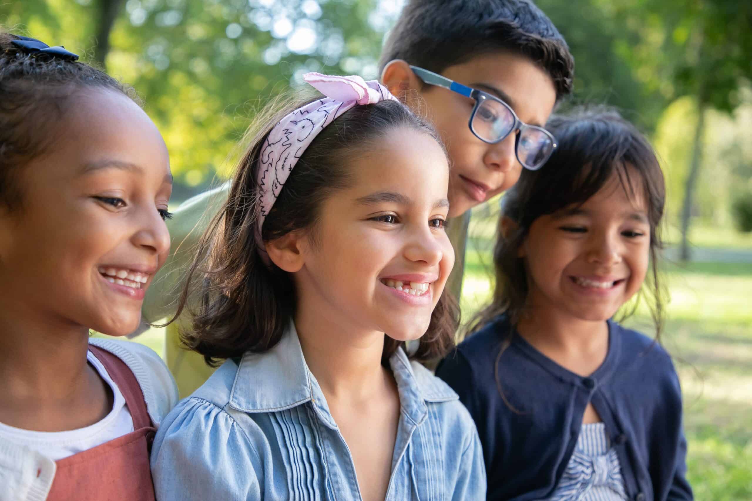 A group of children watch with bright smiles as someone does something off camera.