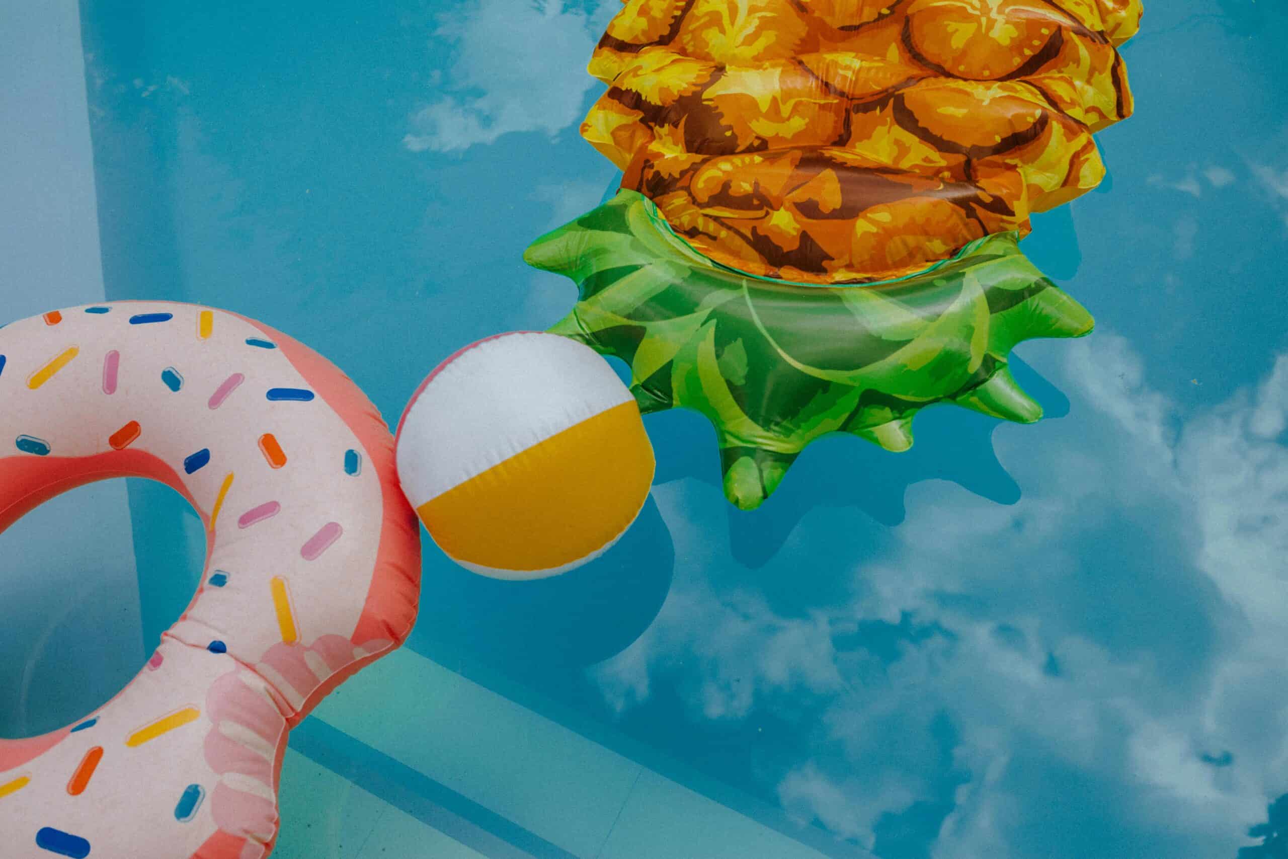 A beach ball, and several pool toys float on the surface of a pool.