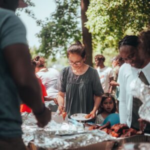 People of different color gather around a picnic table for a cookout.