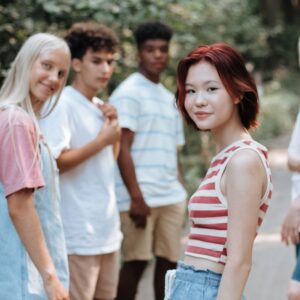 A diverse group of teens walking in the woods look back at the camera.