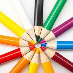 A rainbow assortment of colored pencils all point toward each other in a circle.