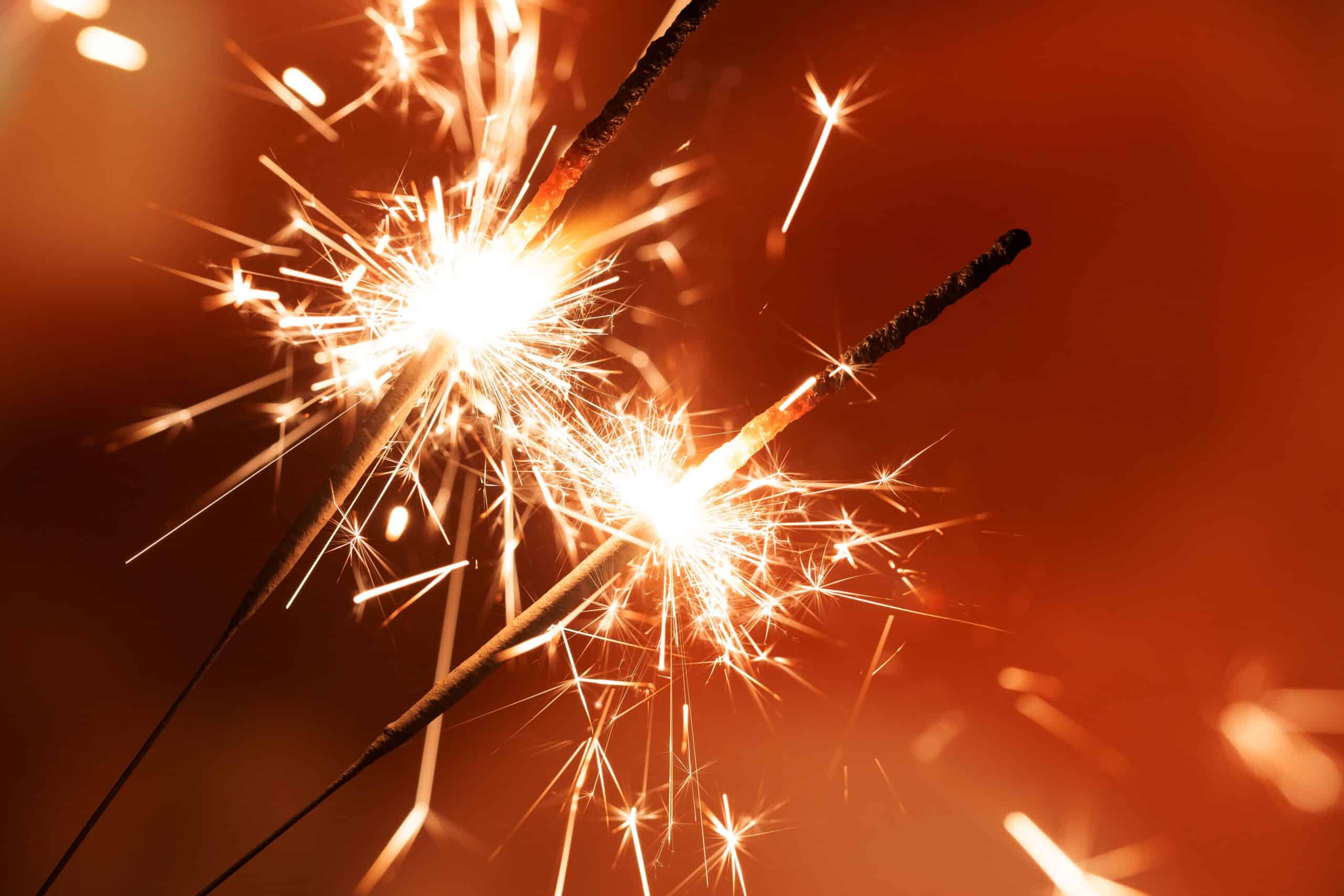 Two sparklers light up the dark.